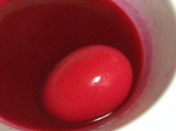 step2: 以大湯碗盛大半碗水，放入適量的紅色食用色素，色澤必須調至深紅，否則上色後顏色會較淺。用湯匙把紅色顏色染滿整集雞蛋，每次染一隻可避免撞裂蛋殼，上色也較均勻。