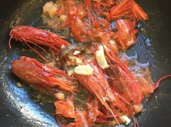 step5: 蝦頭炒熟後加一條鯷魚和蒜頭再炒一分鐘，之後加入白酒 deglaze。