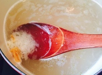 step2: 預備一鍋水，米：水比例約1:10。水滾後倒入米粒（連油）和瑤柱絲。浸瑤柱的水可一併倒入。如有鹹豬手骨，則同時加入骨頭。