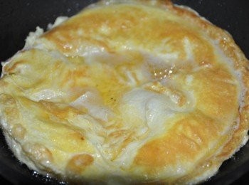 step5: 再快速將蛋挪至平盤中，熱油先倒入另一個容器中，再將蛋回扣再鍋中，熱油再油鍋邊淋入，此時另一邊蛋液也會高高鼓起形成一個厚度