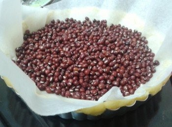 step5: 將烘焙紙放在撻面上，再放一些豆或米在上，然後放入焗爐200度焗5分鐘，再轉180度焗15分鐘