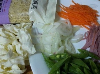 step1: 準備材料:
日式生拉麵 ( 先煮一鍋滾水把麵投入煮50秒即可撈起備用 ) ; 高麗菜                    ( 切絲 ) ; 紅蘿蔔 ( 切絲 ) ; 洋蔥  ( 切絲 ) ; 火腿片 ( 切絲 ) ; 蜜糖豆                   ( 切絲 ) ; 調味料 ( 先用小碗把調味料拌均勻 )