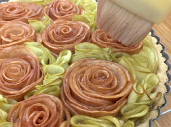 step22: 蘋果玫瑰撻焗好後, 放在架上放涼. 為令顏色更有光澤及保持濕潤, 在蘋果花和葉分別掃上紅色或綠色糖漿.