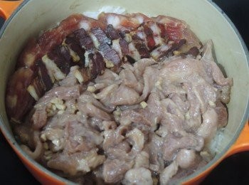 step4: 煲仔開中火加熱煮至水滾，其間用木筷子攪拌。

當水份被白米吸收，見到白米中間有小氣孔後，加入豬頸肉和臘味在白米上。