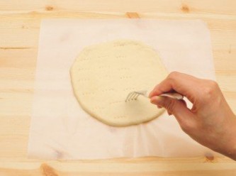step4: 用叉子在麵皮上戳洞後，連同烤盤紙一起放在烤盤上。