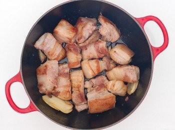 step1: 將五花肉切塊,熱鍋後將五花肉每面煎成焦香狀,煸出油脂,先將五花肉起鍋備用。 沿用原鍋放入薑片及蒜粒拌炒出香氣,加入冰糖小火煮至融化,五花肉也下鍋一起拌炒。