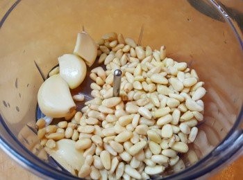 step2: 用平底鑊把松子仁烘烤至微微金黃色後，熄火備用。將松子及蒜放入攪拌機內。