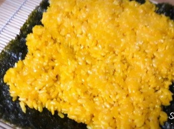 step3: 薑黃飯煮好後 , 用1匙麻油和1匙鹽拌勻 , 均勻的舖到海苔上 , 飯上舖一張保鮮膜 , 然後翻面
