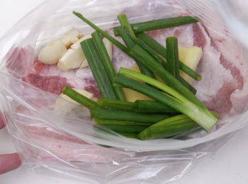 step3: 將五花腩、蒜蔥薑放入慢煮膠袋中，抽出空氣封口，放入容器，再注入滾水至蓋過膠袋