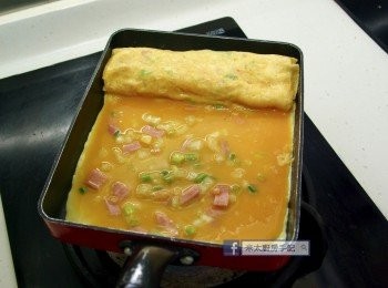 step7: 再放入1/3蛋漿，把蛋卷提起，讓蛋漿流入蛋卷底部，然後用膠刮板把蛋卷往內捲。