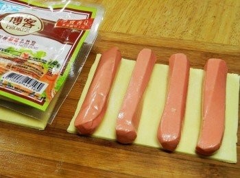 step2: 起酥片切成熱狗長度，塗上蛋液後，鋪上四條博客原味小熱狗