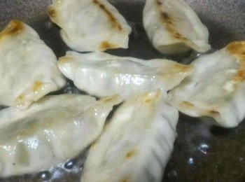 step3: 數分鐘後餃子皮由白色變奶白色, 約8成熟左右, 開蓋, 起底, 小心不要弄穿餃子皮, 繼續煎。