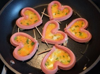 step5: 在腸仔的中央各倒1湯匙蛋液，用鑊鏟按平腸仔的四周，稍煎蛋液至成型固定底部，再平均將剩餘的蛋液放在中央。