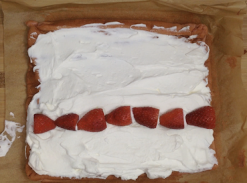 step13: 把定好型的蛋糕體卷開，抹上打好的忌廉，起頭處要多抹，尾段只需輕輕一層即可
草莓切去頂部，放在抹上忌廉的蛋糕體上，大概是三分一的位置，頭尾2粒頂部要向外