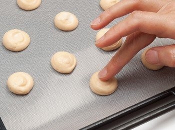 step6: 將麵糊填入已裝好圓形擠花嘴的擠花袋中，在烤盤中擠出圓形的麵糊，然後把手用牛奶（分量外）沾濕，將突起的尖角壓平。