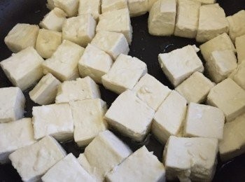 step4: 中火燒熱2匙油在平底鍋子中，加入豆腐粒煎分半鐘，再反轉另一邊