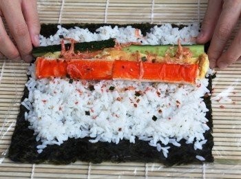 step2: 紙菜放在竹簾上，手上沾一點開水，鋪適量的壽司飯。(米飯要鋪平壓緊，厚度約0.5CM)