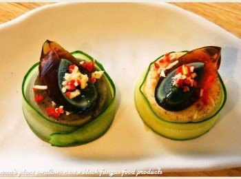 step4: 皮蛋分切成四等份，擺放在黑木耳雪綿酪上後，灑上蒜頭粒與紅辣椒丁。