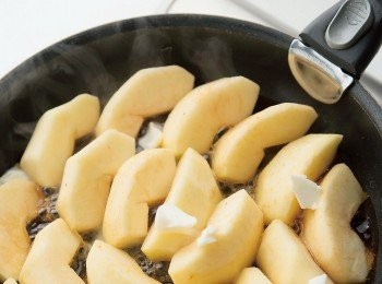 step5: 蘋果削皮、去掉芯和籽，切成6∼8等分。將細砂糖150g與水50㎖倒入平底鍋，用中火加熱到砂糖變焦糖色後，再將一半分量的蘋果整齊排進鍋中。接著把奶油20g切碎後加入。