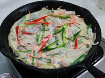 step1: 鐵鍋倒少許油加熱，將<span class="group_2">麵糊</span>材料倒入鍋中搖晃鍋子讓<span class="group_2">麵糊</span>成餅狀後，將紅綠辣椒片放在海鮮餅上