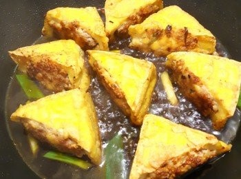 step8: 放入豆腐再下深色醬油一匙，糖、鹽少許 米酒一匙，水一杯，煨燒收汁後即可。