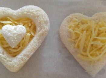 step3: 在印出來的包包上薄搽牛油。。。大心心放在牛油紙上。。。鋪上芝士碎。。。留少少邊位不放。。。然後叠上框框。。。中間再放小心心。。。輕輕按压ㄧ下!