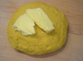 step4: 4. 然後分 2次倒進麵粉中混合，用手揉成一個麵團。麵團揉至不會黏在工作台上，完整地結成一團時，再放入軟化的牛油繼續搓揉。