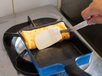 step7: 把鍋子放回爐火上，只煎收口部份，煎時壓著，煎至蛋卷定型不會散開即可上碟。