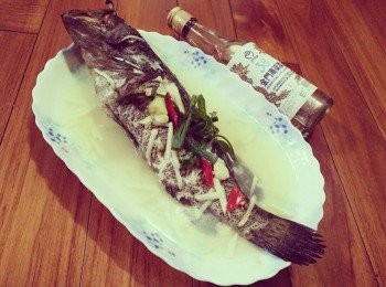 step2: 用大鍋把水燒滾，將澎湖石斑魚放入大火清蒸15分鐘。 並在澎湖石斑魚身上鋪好薑絲，淋上少許的高梁酒和水，經過10分鐘後，把蒜頭放入鍋中，快接近15分鐘後，用筷子插入魚身最厚的地方，筷子若能輕鬆穿過，表示熟透了，如果還沒就多蒸2分鐘後，再試一次。