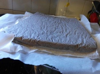 step6: 案板上放一张油纸，将出炉的蛋糕铺在油纸上，趁热撕去底部的烤盘纸