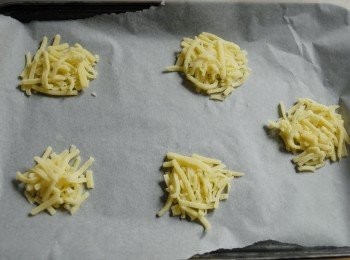 step1: 先將烘焙紙鋪在烤盤上，必定要烘焙紙，不可用其他，否則會黏著做不到的。將芝士碎放在烘焙紙上，分成小份，每份隔有空間