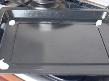step5: 在焗盤的四角塗擠點蛋白霜，再鋪上烘焙紙固定位置