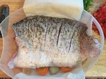 step5: 在蒸魚的容器上先放入一張烘焙紙,等一下蒸好後要移到盤子上會非常方便喔; 接著先將魚放入蒸盤中，底下可以鋪些紅蘿蔔片，或者將醃魚的薑片和蔥段墊在魚下方，帶皮的面朝上。如家裡蒸鍋夠大，就可以直接擺在盤子上，但下面還是要墊些薑片把魚撐高。