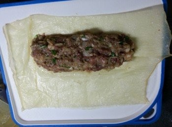 step8: 將豬肉分成六份,將一塊腐皮用手抹水搽濕腐皮,(必須係包時才整濕,否則腐皮會爛)放入一份豬肉於腐皮上卷起成長方型