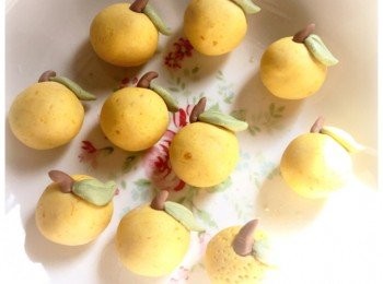 step3: 用造好的南瓜粉團搓成圓型年桔形狀，再用綠茶粉團造出葉子形狀，點些清水將樹葉黏在年桔上，即成年桔湯丸。想質感更神似，可用牙籤在表面插一點小洞。