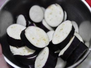 step3: 茄子切成薄圓片，再放入熱油鍋中炸約20秒撈起瀝油，炸過的鮮茄可以保持它的鮮紫色喔~