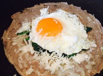 step6: 鑊中無需加油，開小火，放入煎好的餅皮。在中央鋪上菠菜，再放上太陽蛋。在蛋的四周盡情灑上Mozzarella芝士碎，用小火慢慢將芝士烘溶。