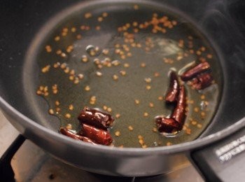 step5: 麻油倒入鍋中後開中火加熱，紅辣椒切半，炒至辣椒與辣椒籽變黑。