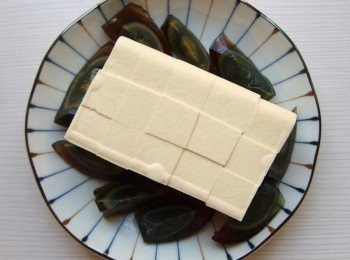 step2: 將嫩豆腐放在盤子上切成方塊狀(但不切斷),方便食用。皮蛋去殼切片。