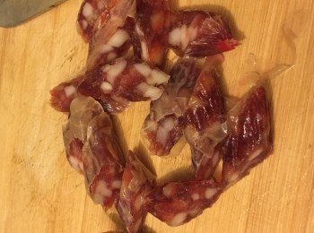 step1: 先把洋蔥切絲，蒜頭切碎備用。粉絲可剪兩下，然後用熱水浸泡5分鐘，瀝乾備用。把臘味放入熱水中浸泡5分鐘，然後洗淨斜切片備用。