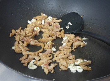 step2: 易潔鑊下2湯匙油燒熱，下肉絲用中火兜炒至半熟, 下蒜粒炒至肉絲熟透，贊酒炒兜炒，