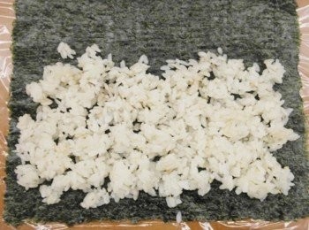 step7: 在桌上鋪上一張保鮮膜..接著鋪上海苔片!! 把白飯適量的舖在海苔上約2/3即可..不需要整張都鋪白飯唷^^" 白飯也不用鋪太厚因為之後還要加料上去~~