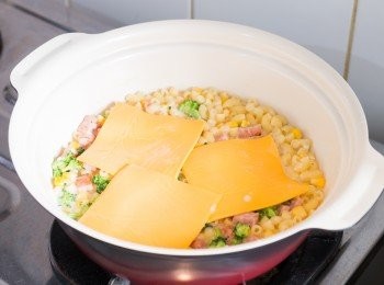 step8: 多煮 4 分鐘後，通心粉應該就煮熟了然後大部份水份都被吸收了。 關火後加入芝士片拌至芝士片溶化，讓剩餘的水份都變成濃稠的醬汁。