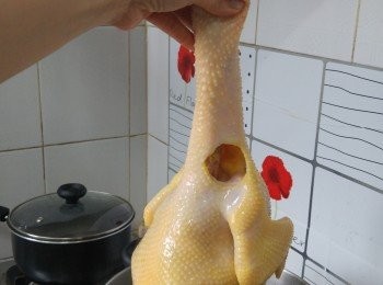 step3: 以蓋面無洞的大煲燒一煲水(密封煲較為存熱)，放入2片薑，要足以蓋過全雞，水大滾後手執雞頸， 將雞身放進滾水中浸2秒後拿起， 重複3次， 可令雞腔內外溫度均勻。