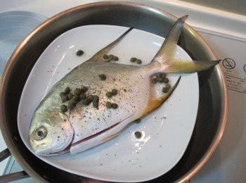 step2: 將魚雙面和肚子內抹鹽。 灑上胡椒及酸豆淋上少許米酒放入鍋用中火蒸5分鐘後，放入切好的蕃茄進來。