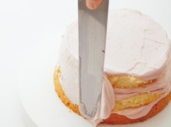 step6: 再次放上奶油霜，在蛋糕表面水平移動抹刀，將奶油霜抹開。
側面抹上適量的奶油霜。將抹刀約傾斜10度
快速旋轉蛋糕轉台，將側面的奶油霜抹成光滑平整的狀態
【將外層的側面塗得稍微厚一些，接下來就會更方便作業。】