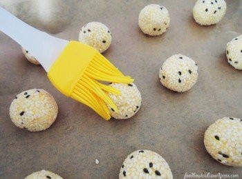 step5: 将南瓜芝麻球摆在铺好烘焙纸的烤盘上再刷上薄薄一层的芝麻油。预热烤箱在220度，烘烤12-15分钟至到外皮呈现酥脆金黄色即可。（你可选择以热炸的方式）