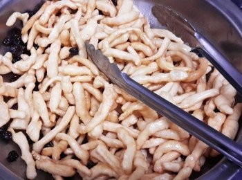 step5: 將炸好的麵條（可加葡萄乾，芝麻等）放入鍋內與糖漿拌勻 將炸好的麵條（可加葡萄乾，芝麻等）放入鍋內與糖漿拌勻