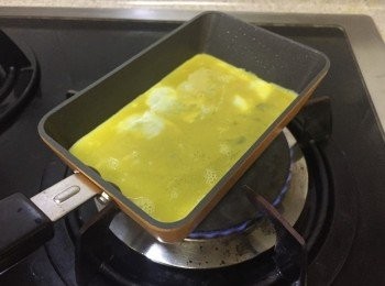 step3: 將約2匙的蛋汁平均倒入煎pan上，四角也滿滿的，薄薄一層即可，最細火煎至8成凝固後，用筷子或平煎鑊子由底部的蛋皮卷向上，另一邊手可以不時將煎pan提起左右擺動方便卷起