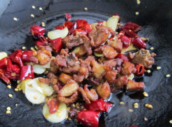 step4: 鍋中留少許底油，放入姜蒜片，幹辣椒、花椒粒炒出香味，再放入炸好的雞肉翻炒。